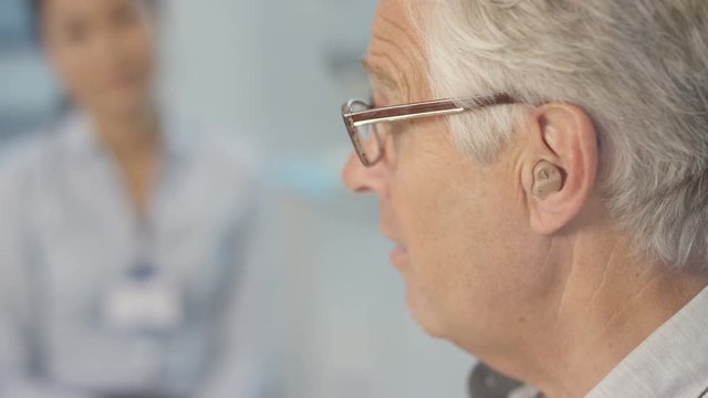  Mature man with deafness being fitted for hi tech hearing aid