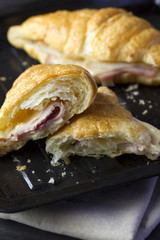 Plit butter croissant with ham and cheese sandwiches on old black baking tray