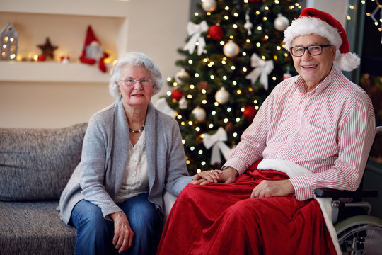 portrait of senior man in wheelchair and smiling woman with Christmas gift.
