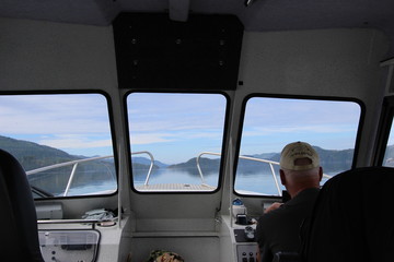 Older Man Driving A Boat Looking Out Window