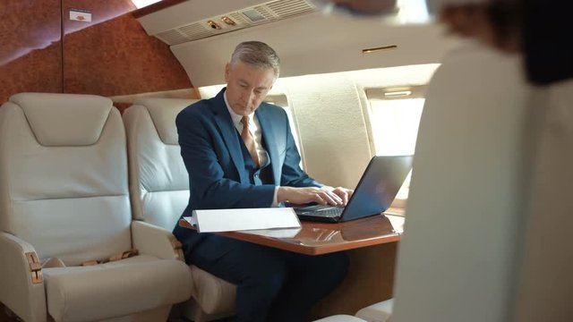  Air hostess serves champagne to businessman traveling on private plane