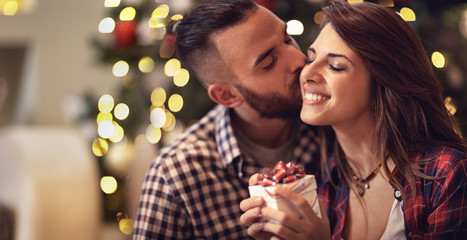 Obraz na płótnie Canvas Man kisses woman while gives her Christmas gift