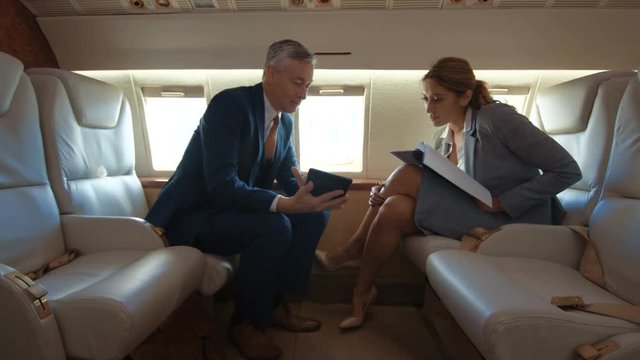  Business man & woman looking at tablet during flight on private plane