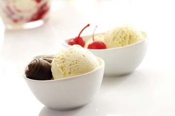 Bowls of vanilla ice cream garnished with chocolate pralines and maraschino cherries