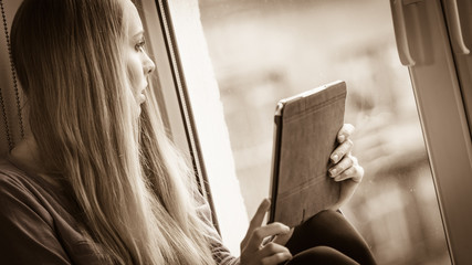 Student girl with tablet sitting on windowsill