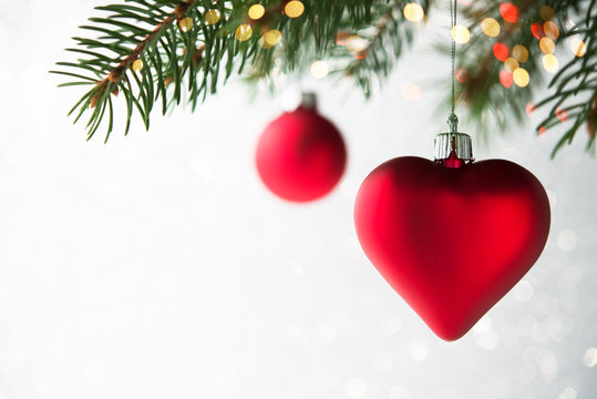 Red christmas ornaments, heart and ball, on the xmas tree on glitter bokeh background with twinkle lights. Merry christmas card. Winter holiday theme. Happy New Year.