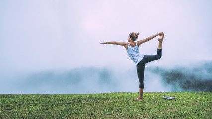 Fototapeta na wymiar Asian women relax in the holiday. Play if yoga, natural forests, mountains and mist.