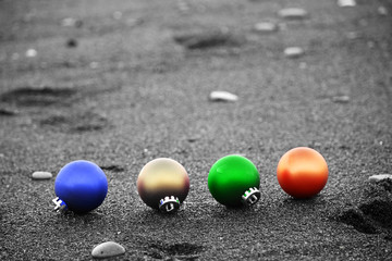 Colorful Christmas ornaments on black sand