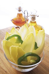 Chicory and green capsicum in a glass bowl, oil and vinegar in background