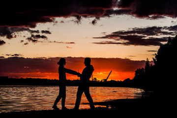 man and woman dancing in the sunset holding hands. Romantic evening. Love.