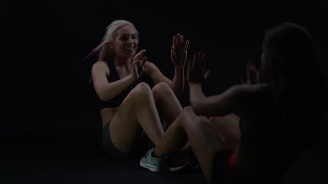  2 Fit women working out together, doing sit ups with feet interlocked