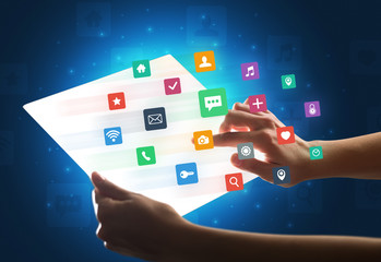 Hands touching a glass-like tablet with colorful icons
