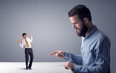 Young businessman fighting with miniature businessman