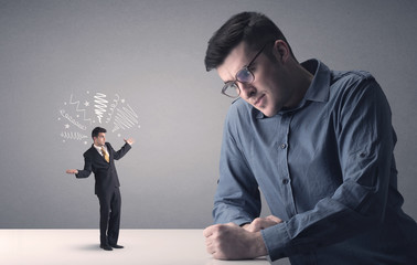 Young businessman fighting with miniature businessman