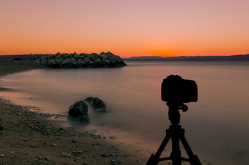 Camera on tripod with ocean and sunset in background / Podgora, Croatia