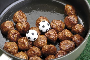 Football fast food - meatballs in a pan with two miniature footballs