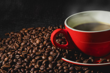 Hot coffee in red cup and coffee beans are the background.