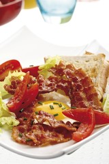 Breakfast bacon, a fried egg, toast and tomatoes