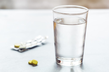 Pills, with a glass of water on a background. Treatment with medicines. 