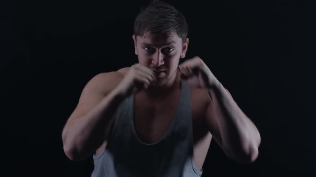  Muscular boxer training, throwing punches towards camera with bare fists