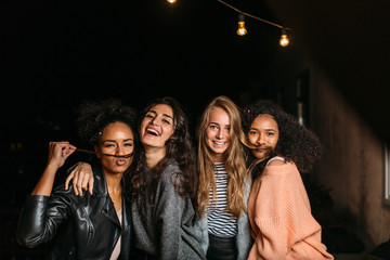 Fototapeta premium Shot of female friends having fun at night, looking at camera