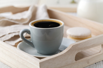 Cup of coffee and macaron cakes on tray on white wooden table