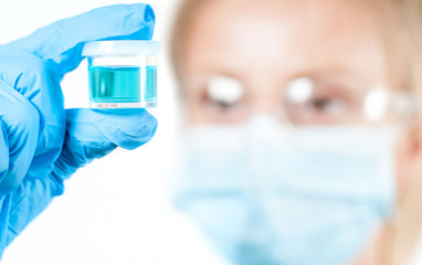 Chemist in protective eyeglasses holding test tube with reagent in lab