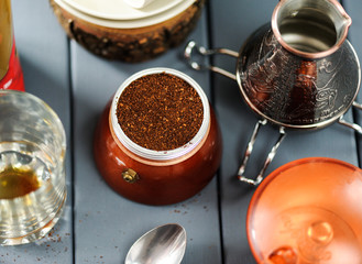 Italian moka coffee pot with grind coffee and cezve on grey background