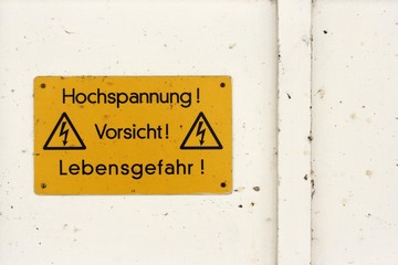 High tension! Caution! Danger! Instruction and warning sign on a house wall