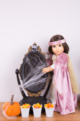 Halloween decoration. An 18 inch doll wearing Halloween costume. A decorative mirror covered in cobweb. Candy corn in a tiny metal buckets. 