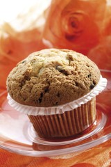 Muffin set on an orange tablecloth, floral arrangement in background