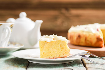Homemade delicious cake with cream icing served with tea on shabby wooden table