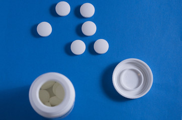 pink and white pills lying on the blue table