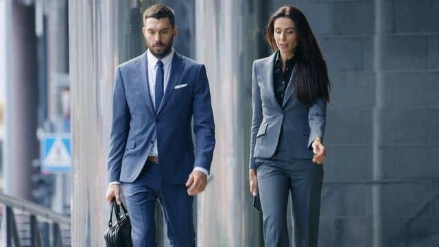 Male and Female Business People Walk and Financial Matters. They're Work in the Central Business District. Shot on RED EPIC-W 8K Helium Cinema Camera.