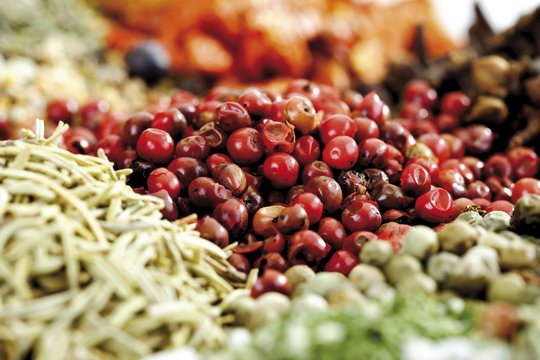 Various spices, pink peppercorns in focus