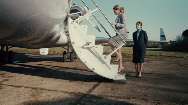  VIP Businesswoman is greeted by stewardess before boarding private plane