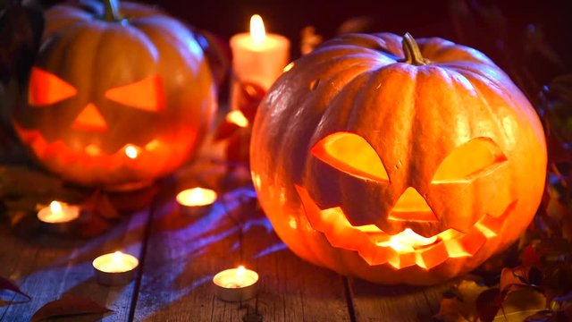 Halloween pumpkin head jack lantern with burning candles over wooden background. Full HD video 1920X1080