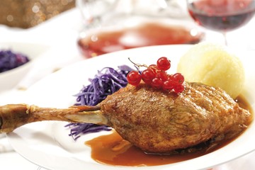 Goose-leg, red cabbage, potato dumpling on a festively decorated table