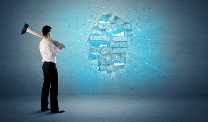 Business man hitting brick wall with huge hammer