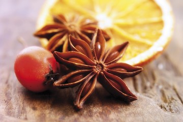 Star anise, dried orange slice and rose hip on a wooden base