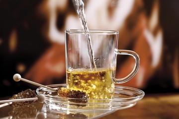 Pouring grog into a glass, garnished with rock candy in front of a fireplace