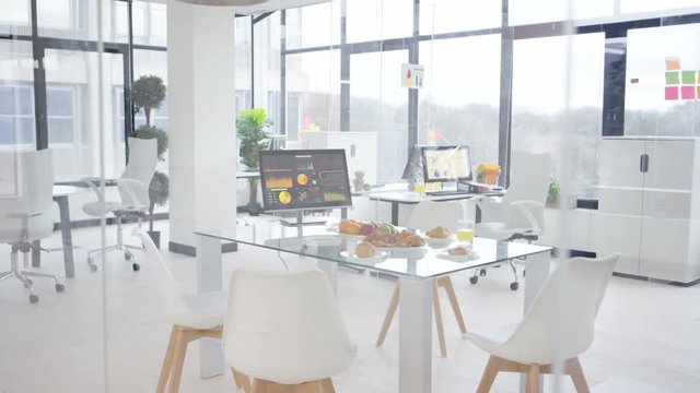  Interior empty office, desk laid with fruit & pastries for morning meeting