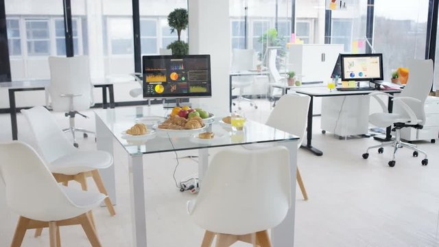  Interior empty office, desk laid with fruit & pastries for morning meeting