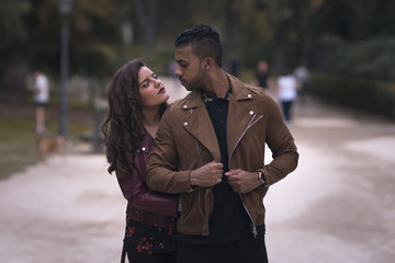 Fototapeta premium Young male and female couple hugging and looking each other in the street