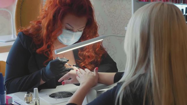 Female red makes a spa procedure for the fingernails of the client