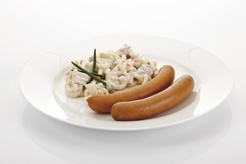 Two sausages on a plate with pasta salad