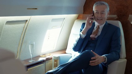 Successful businessman talking on phone while traveling by private plane - Powered by Adobe
