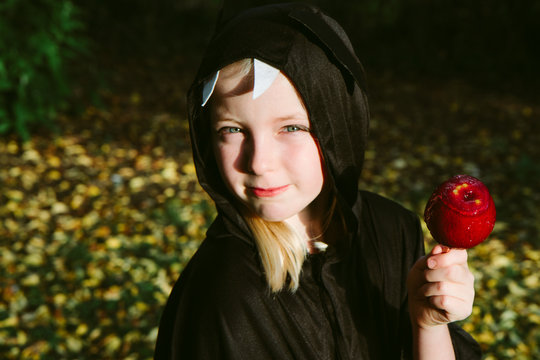 A Little Girl Dressed As A Bat Eating A Candy Apple