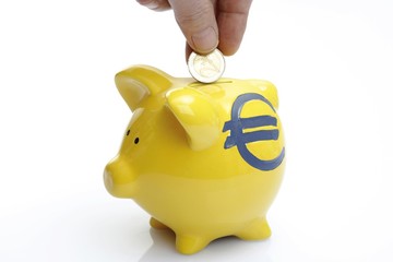 Hand dropping a coin into a piggy bank with Euro symbol