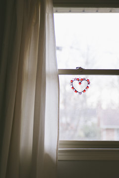 A serene image of a window with a heart ornament.